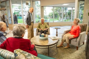 Group of seniors sitting and standing in a common area at Piedmont Gardens