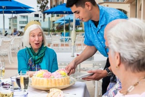 Server slicing birthday cake for seniors