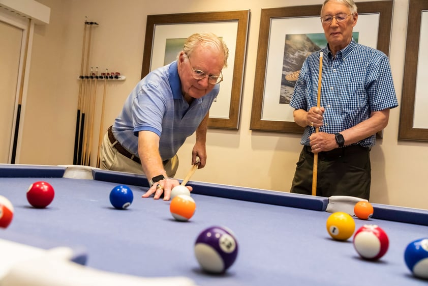 Two senior men playing a game of pool