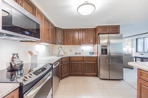 Kitchen with dark wood cabinets and stainless steel appliances in a home at Rydal Park & Waters