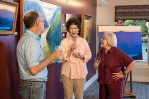 Three seniors drinking wine in an art gallery