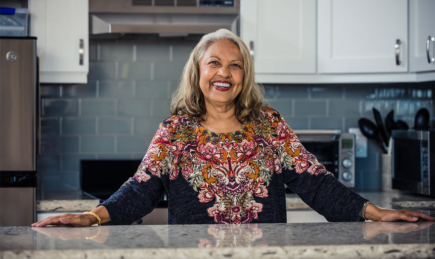 Smiling senior woman standing at a granite counter in a kitchen