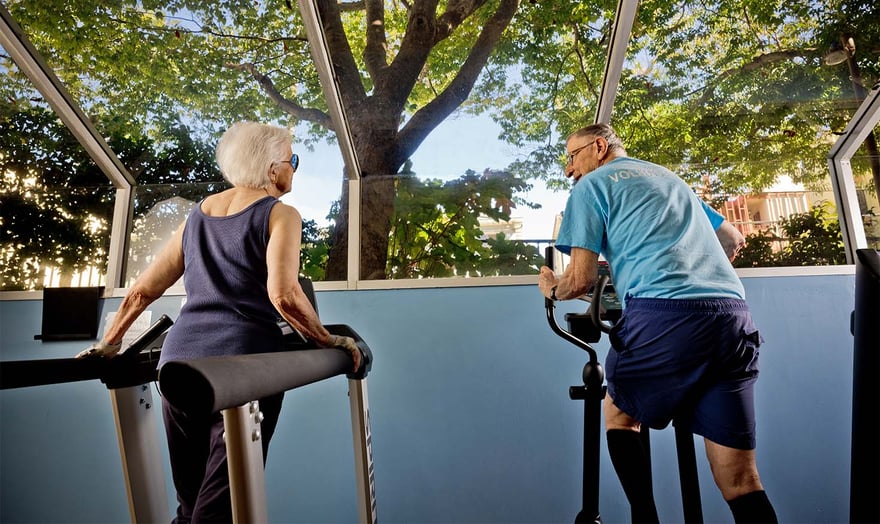 Senior man and woman using exercise equipment in the fitness center at Piedmont Gardens