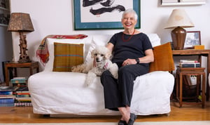 Senior woman sitting on a couch with a small white dog