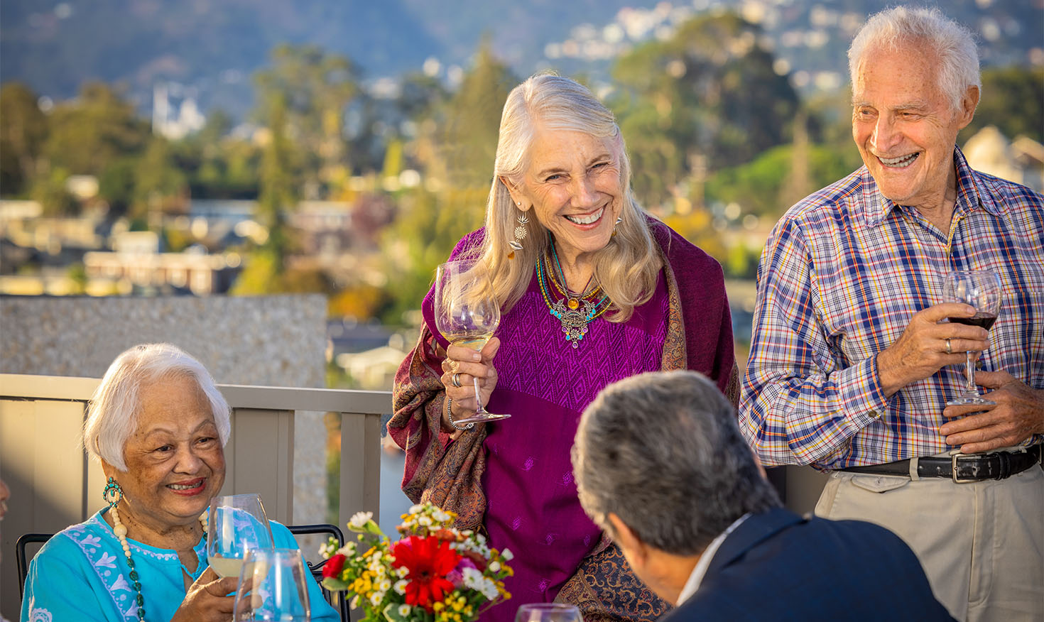 Four seniors enjoying glasses of wine on an outdoor patio