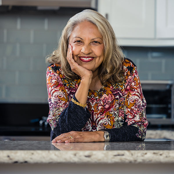 Smiling senior woman leaning on a granite countertop in a kitchen