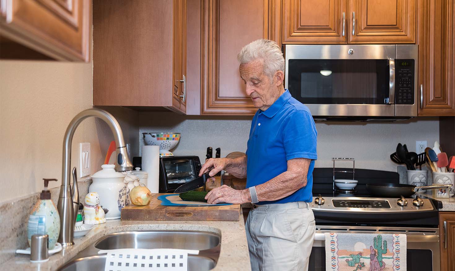 Senior man chopping vegetables in the kitchen of his home at Redwood Terrace