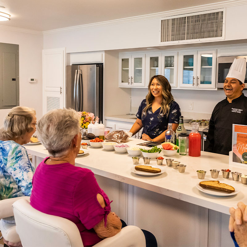 Group of seniors sitting at a kitchen island with ingredients set out on it for a cooking class  