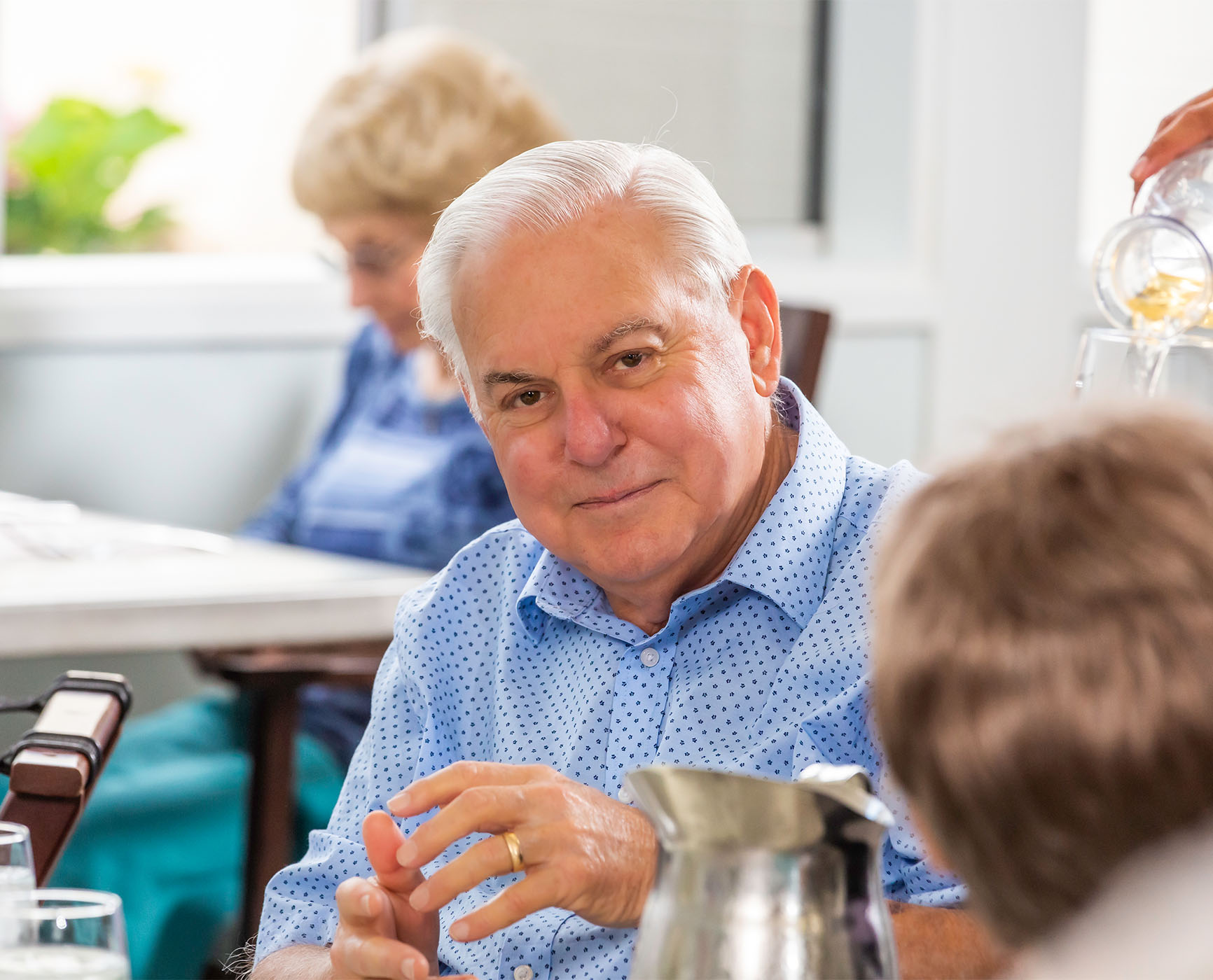 Senior man sitting at a dining table in the dining room at Redwood Terrace