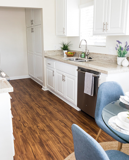 Kitchen with white cabinets, granite countertops, and wood floors in a home at Redwood Terrace