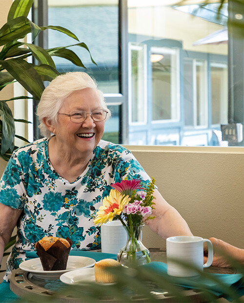 Senior enjoying a muffin and coffee in the cafe at Redwood Terrace