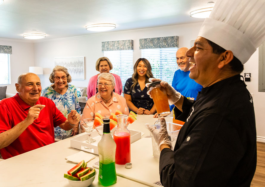 Group of seniors gather around as a chef prepares mixed drinks