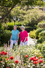 two women walking through a flower garden