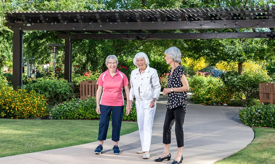 Three senior women walking and talking outside of a gazebo on the campus of Rosewood