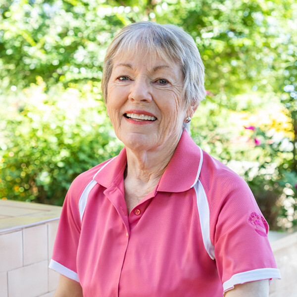 Close-up of a smiling senior woman in a pink polo shirt