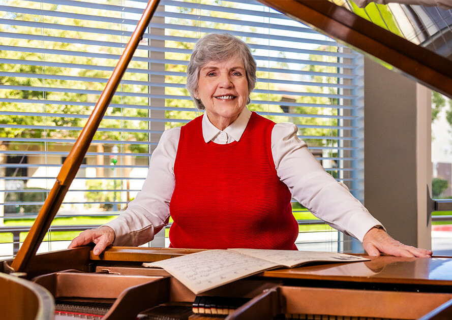 Senior woman standing at a piano