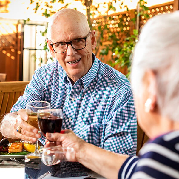 Senior couple toasting with wine glasses on the patio at Royal Oaks