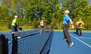 Four senior men playing pickleball on an outdoor court
