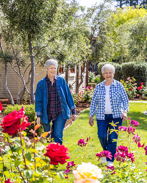 Two senior women walking in the garden at The Terraces at Los Altos