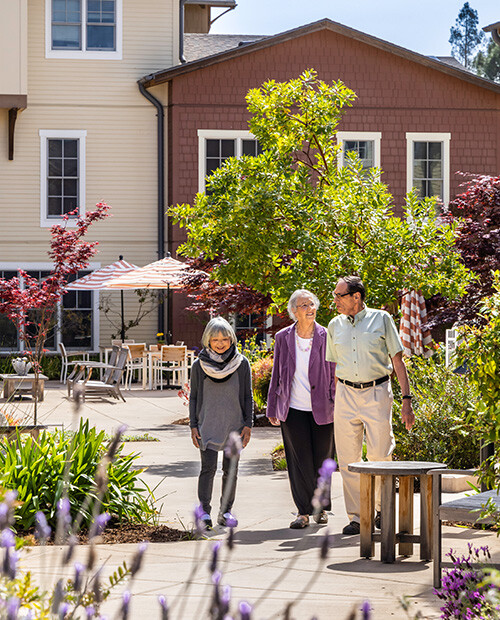 Two senior women and a senior man walking through the grounds of The Terraces at Los Altos