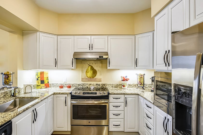 Kitchen with white cabinets, granite countertops and stainless steel appliances in an apartment at The Terraces at Los Altos