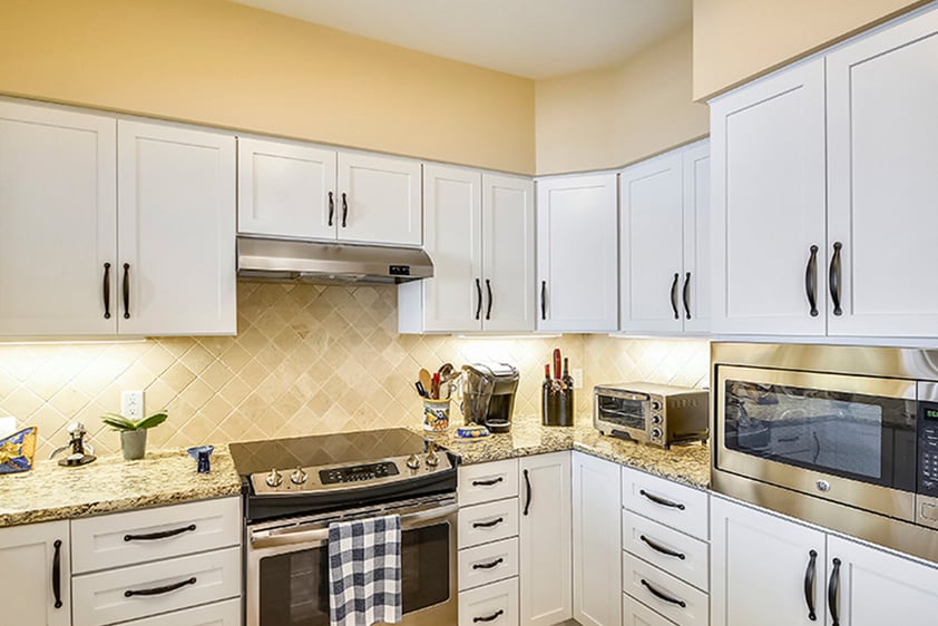 Kitchen with white cabinets, granite countertops and stainless steel appliances of an apartment at The Terraces at Los Altos