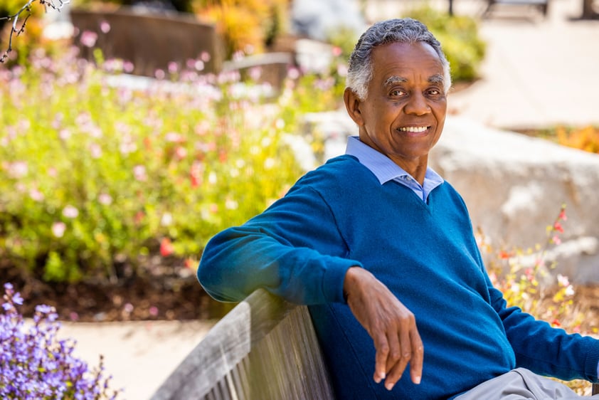 Senior man sitting on a bench in the garden at The Terraces at Los Altos