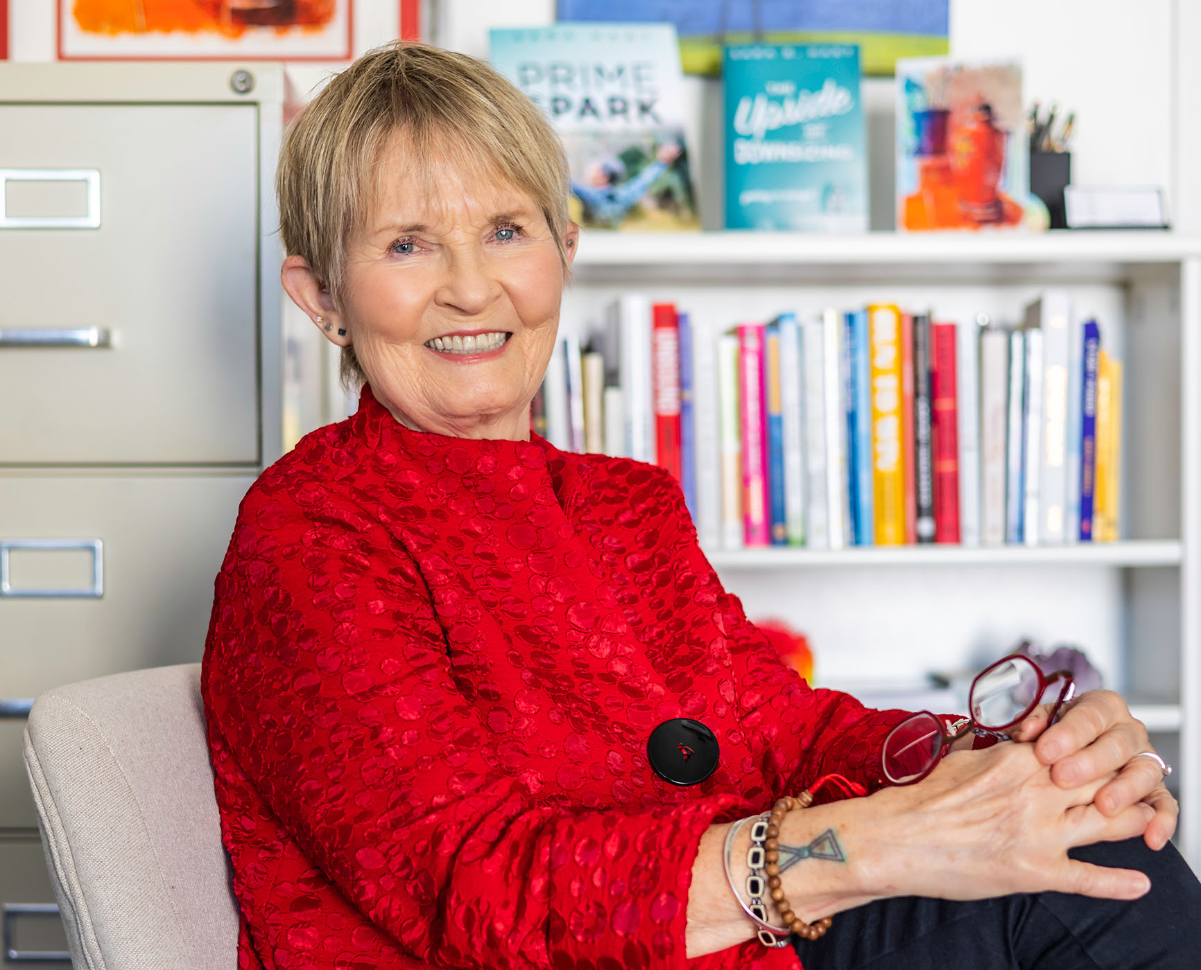 Smiling senior woman sitting in front of bookshelf