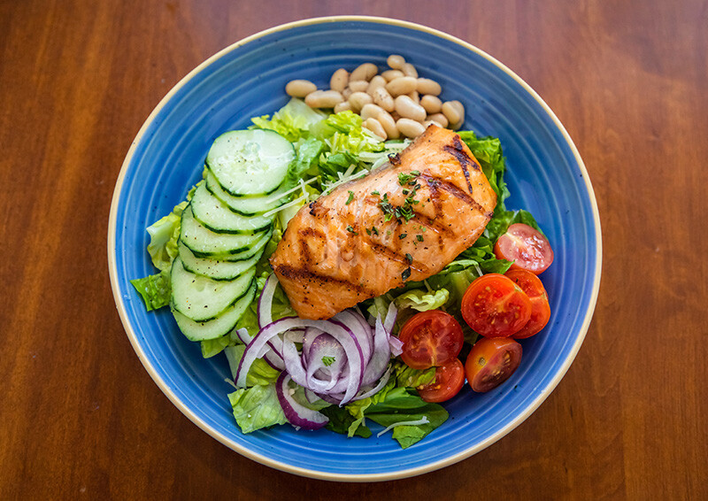 Salmon filet on a bed of lettuce, cucumber, onion, tomato and beans