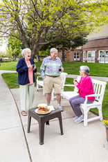 Senior woman on a park bench talking to a standing senior man and senior woman