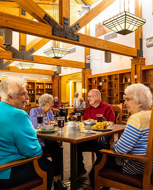 Group of four seniors eating dinner in the dining room at The Terraces of Summitview