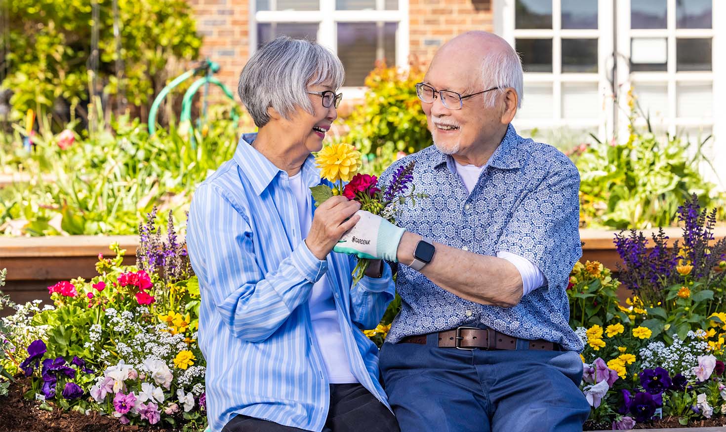 Senior woman and senior man holding flowers in the garden at The Terraces at Summitview