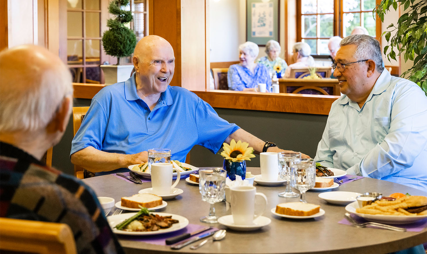 Three senior men eating lunch in The Terraces at Summitview dining room