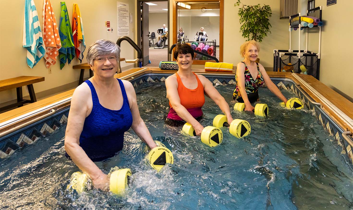 Three senior women using water weights in a water exercise class