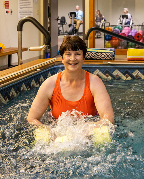 Senior woman using water weights in a water exercise class