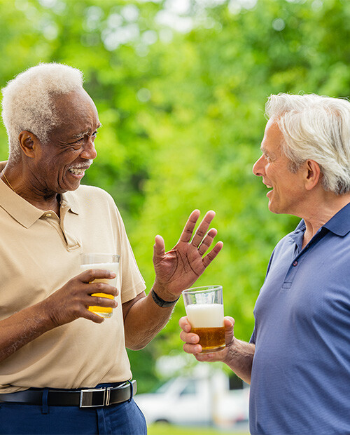 Two senior men holding glasses of beer and talking