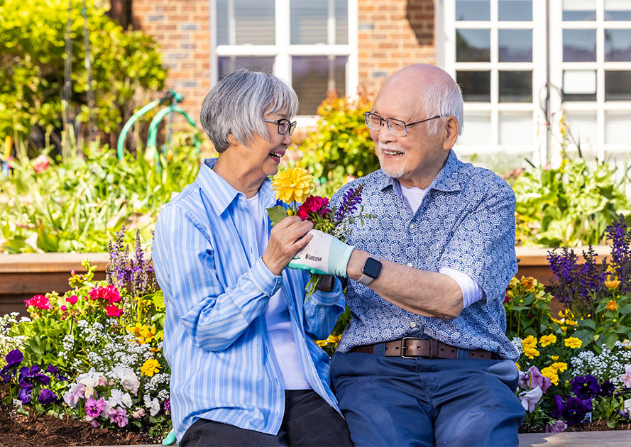 Senior woman and senior man holding flowers in the garden at The Terraces at Summitview