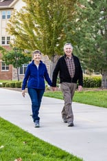 Senior couple holding hands and walking through the community