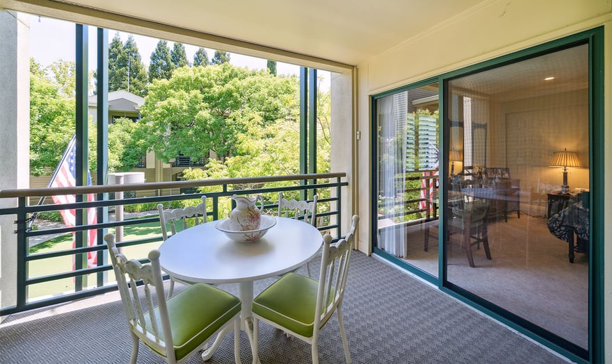 Covered patio with outdoor furniture looking into the living room of an apartment at The Terraces of Los Gatos