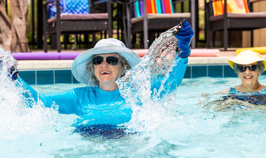 Senior woman wearing a sun hat doing water aerobics in an outdoor pool