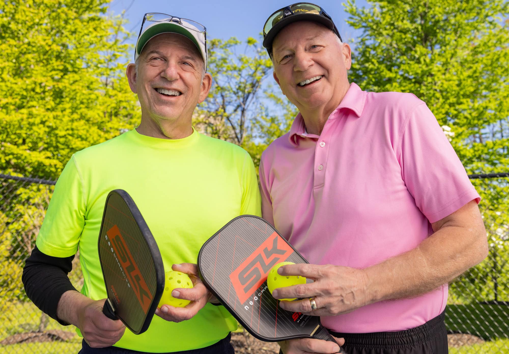 Two men holding pickleball paddles 