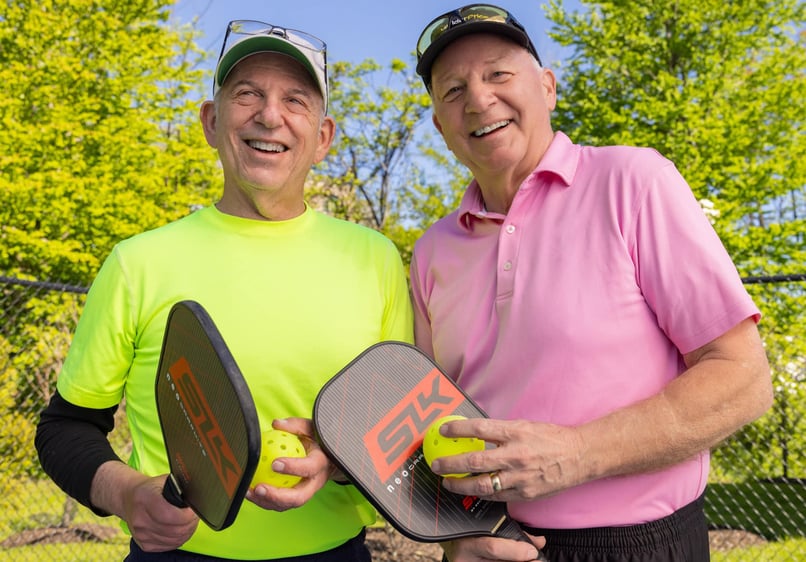 Two men holding pickleball paddles 