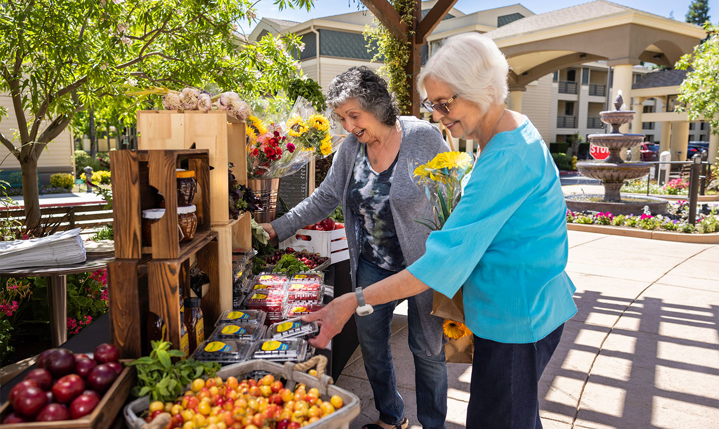 Two senior women shopping for produce and flowers at a farmers market