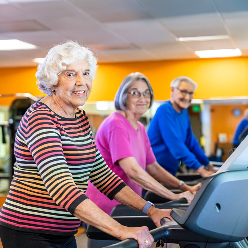 Seniors walking on treadmills in the fitness center at The Terraces of Los Gatos