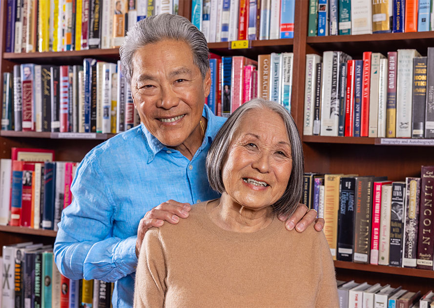 Senior couple smiling in front of the bookshelves in a library