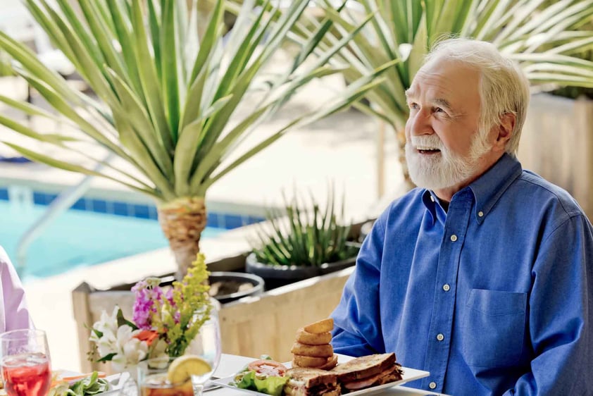 Senior man eating lunch by the pool