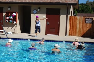 Group of seniors in a water aerobics class in the outdoor pool with instructor