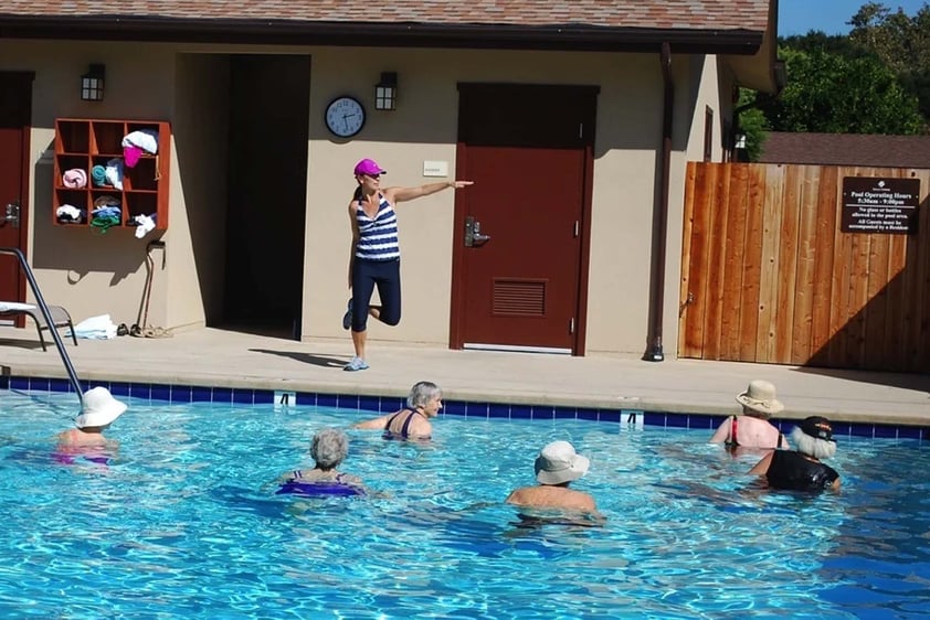 Group of seniors in a water aerobics class in the outdoor pool with instructor