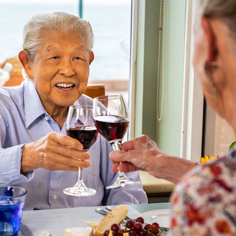 Seniors toasting with glasses of red wine at lunch