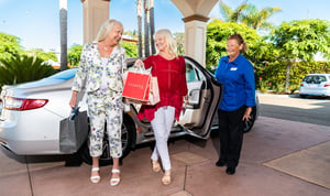 Two senior women exiting a car, arriving back at the community after a shopping outing